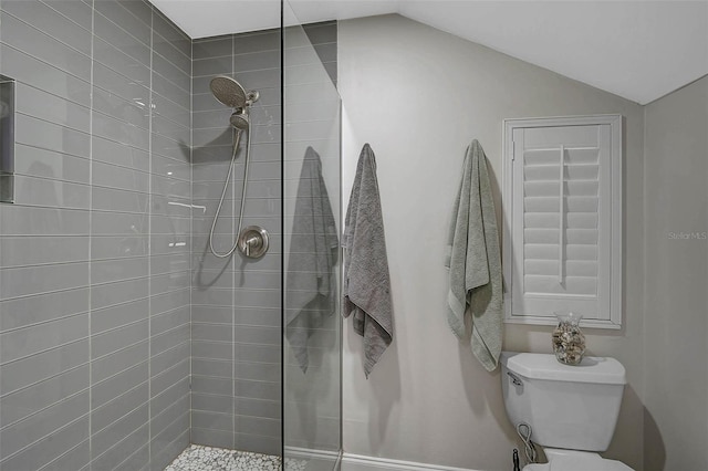 full bathroom featuring lofted ceiling, toilet, and a tile shower