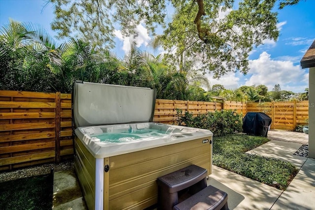 view of patio / terrace with a hot tub, fence, and grilling area