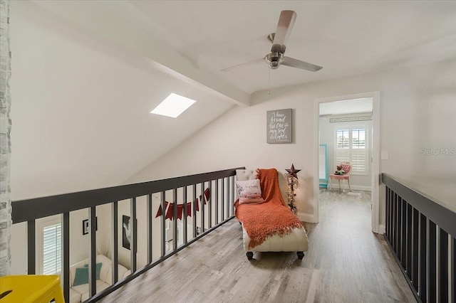 interior space with vaulted ceiling with skylight, baseboards, ceiling fan, and wood finished floors