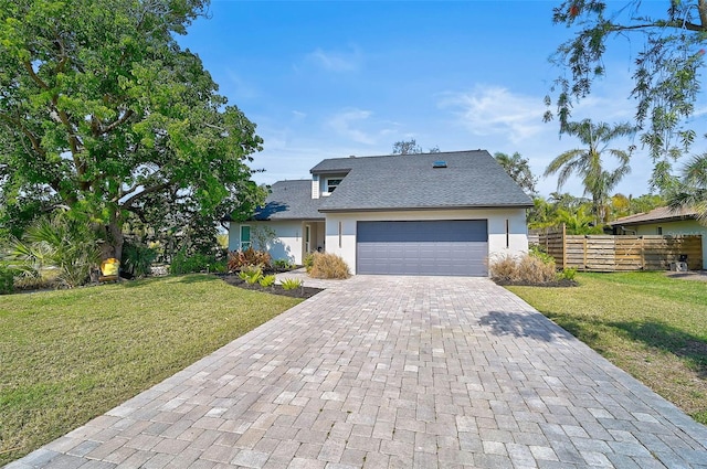 view of front of home featuring an attached garage, decorative driveway, a front yard, and fence