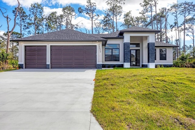 prairie-style home with a garage, concrete driveway, a front yard, and stucco siding