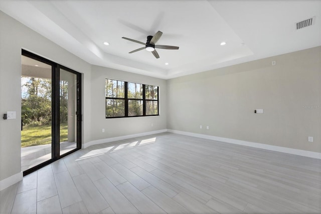 empty room featuring a tray ceiling, baseboards, and recessed lighting