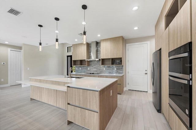 kitchen with a center island with sink, visible vents, modern cabinets, hanging light fixtures, and black appliances