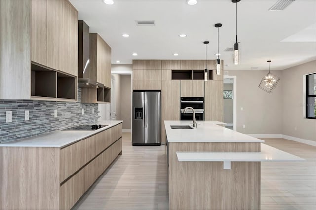 kitchen featuring light countertops, wall chimney range hood, black appliances, modern cabinets, and a large island with sink