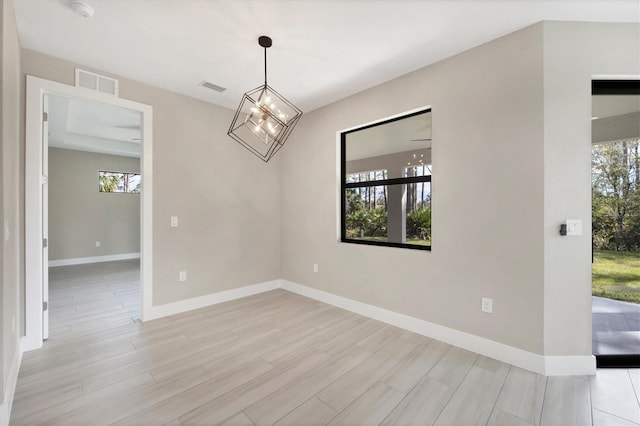 empty room with a wealth of natural light, visible vents, and light wood finished floors