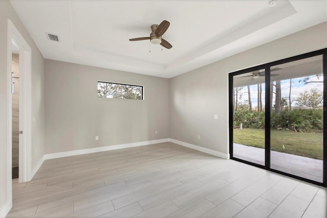 unfurnished room featuring a tray ceiling, a healthy amount of sunlight, and visible vents