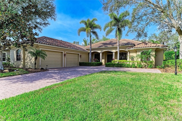 mediterranean / spanish house with a garage, a tile roof, decorative driveway, stucco siding, and a front yard