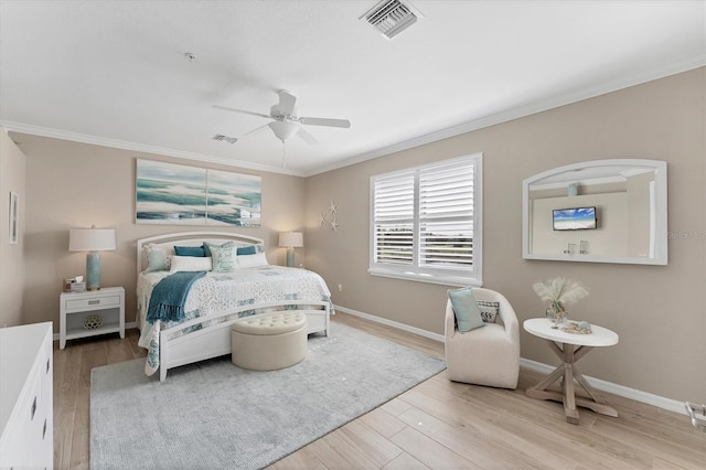 bedroom featuring light wood finished floors, baseboards, visible vents, and crown molding