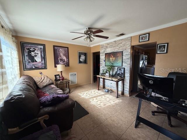 living area featuring ceiling fan, visible vents, crown molding, and light tile patterned floors