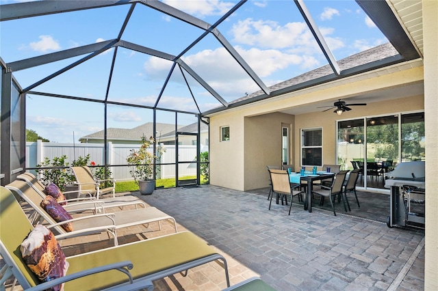 view of patio with ceiling fan, a grill, and glass enclosure