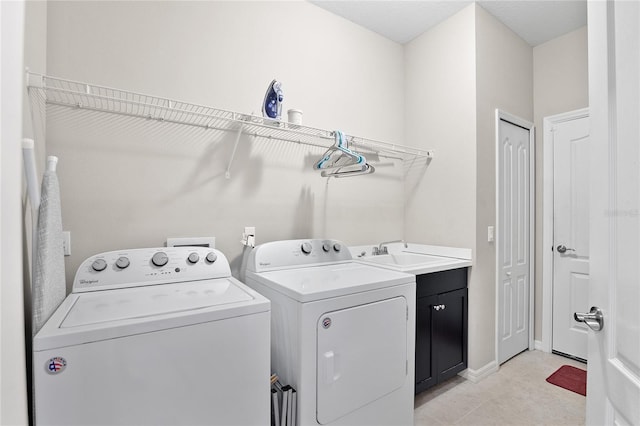 laundry room with light tile patterned flooring, cabinets, washer and dryer, and sink