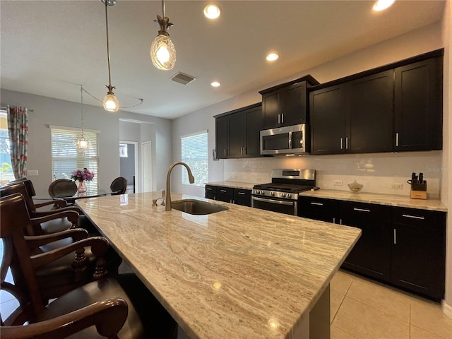 kitchen featuring a center island with sink, pendant lighting, stainless steel appliances, and sink