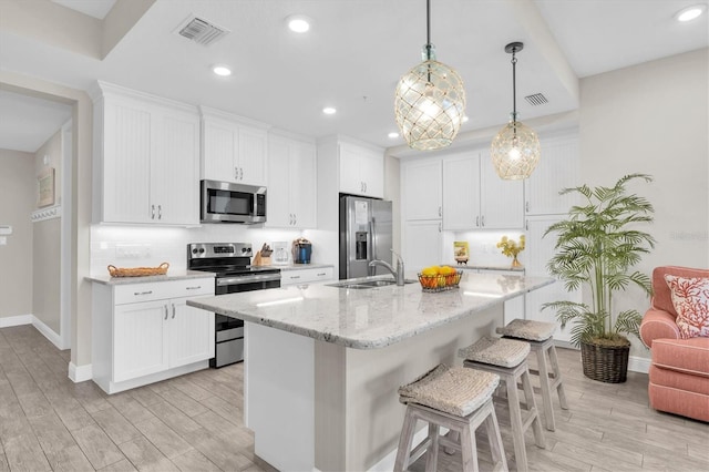 kitchen with stainless steel appliances, light wood-style floors, visible vents, and a kitchen breakfast bar