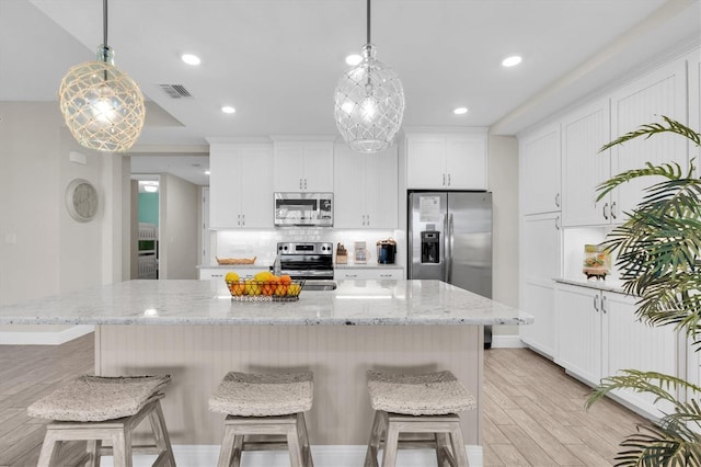 kitchen with visible vents, white cabinets, light wood-style floors, appliances with stainless steel finishes, and decorative backsplash