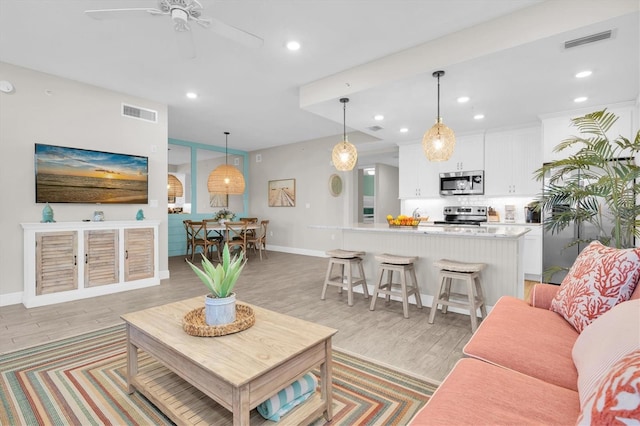 living area with ceiling fan, light wood-type flooring, visible vents, and recessed lighting