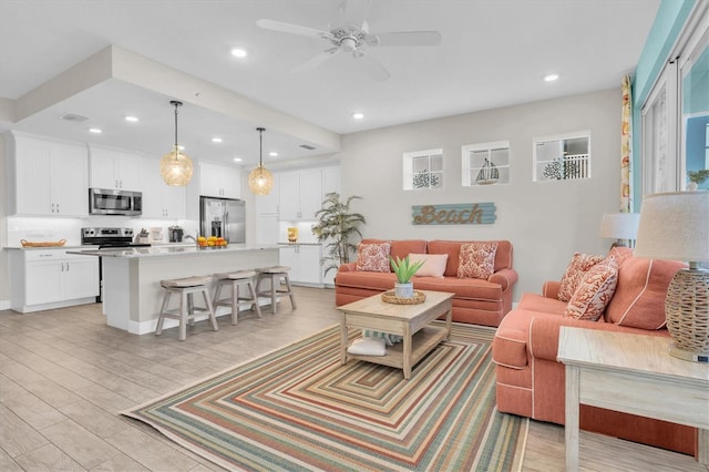 living room featuring a ceiling fan, light wood-type flooring, and recessed lighting