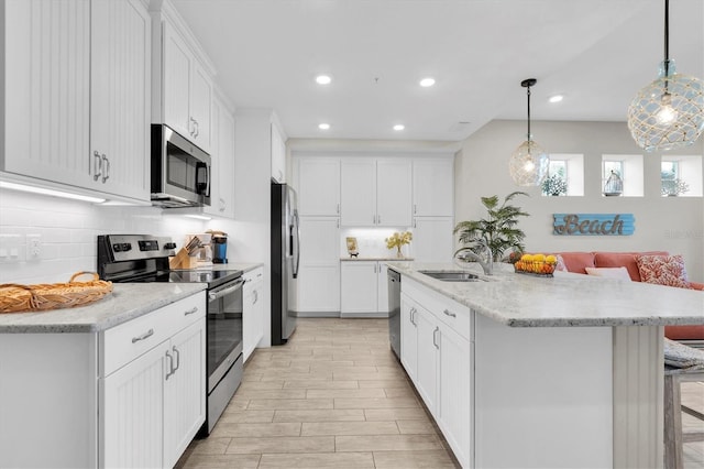 kitchen featuring stainless steel appliances, backsplash, a sink, and white cabinets