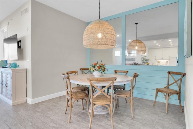 dining room with light wood-style floors, baseboards, and visible vents