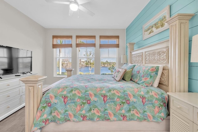 bedroom featuring wood finished floors, a ceiling fan, and wooden walls