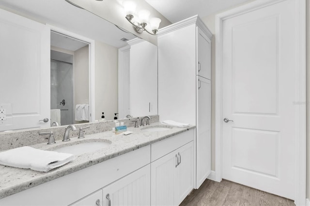 full bathroom featuring double vanity, wood finished floors, a sink, and visible vents