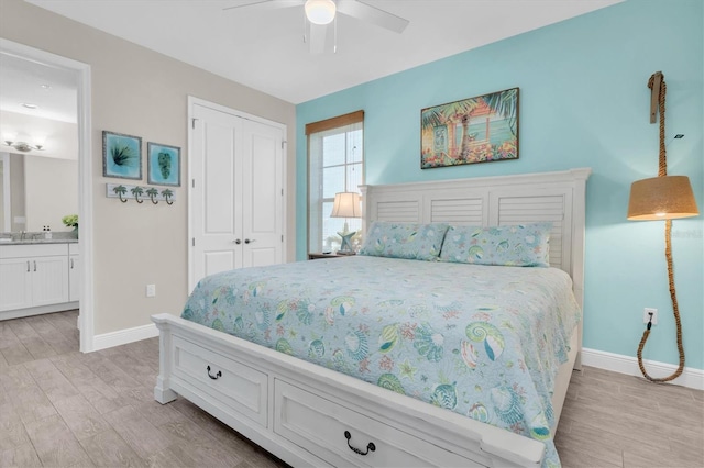 bedroom featuring a closet, light wood-type flooring, ensuite bath, and baseboards