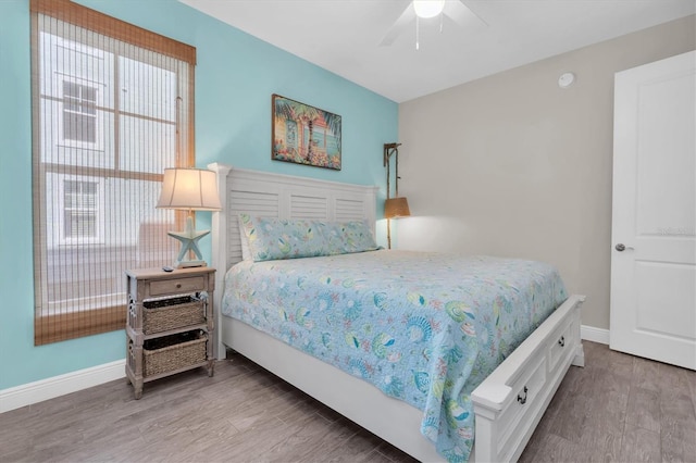 bedroom with a ceiling fan, baseboards, and wood finished floors