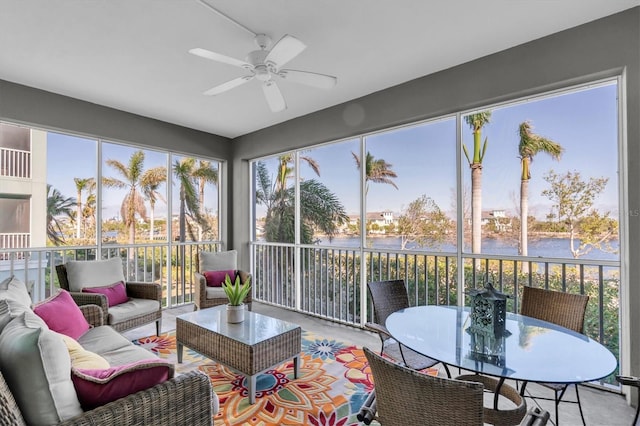 sunroom / solarium with ceiling fan, a water view, and a wealth of natural light