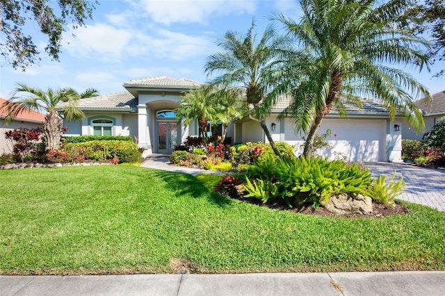 view of front of property featuring decorative driveway, stucco siding, an attached garage, a front yard, and a tiled roof