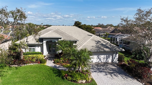 view of front of home featuring a garage, a tiled roof, decorative driveway, a front yard, and stucco siding