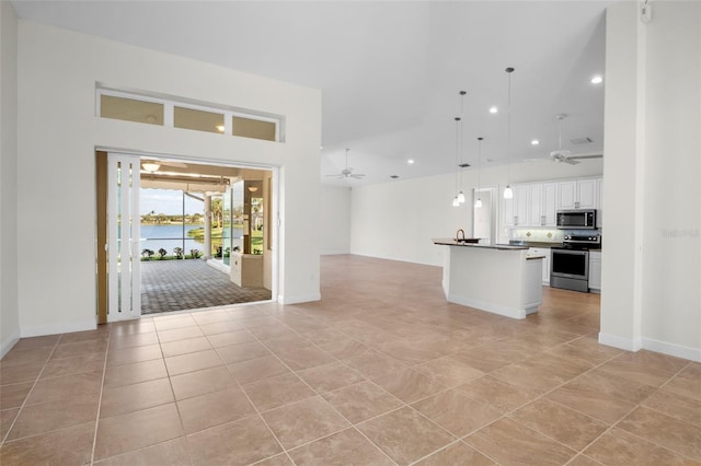 kitchen featuring white cabinets, a ceiling fan, dark countertops, appliances with stainless steel finishes, and open floor plan