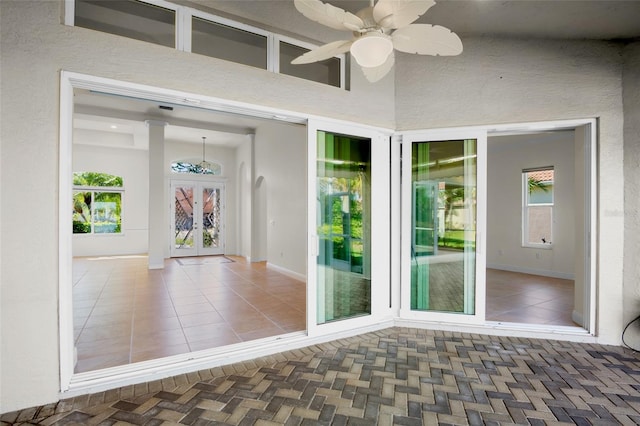 interior space with ceiling fan, plenty of natural light, a towering ceiling, and baseboards