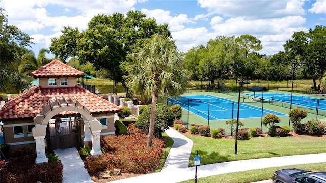 view of tennis court featuring fence and a lawn