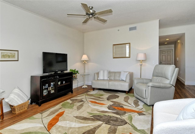 living area with visible vents, a ceiling fan, a textured ceiling, wood finished floors, and baseboards
