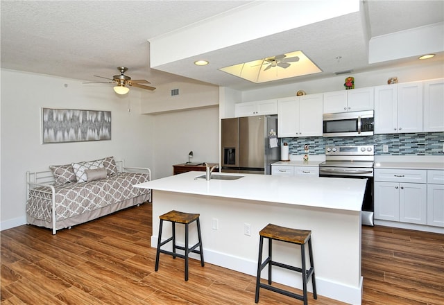 kitchen featuring a breakfast bar, a center island with sink, light countertops, appliances with stainless steel finishes, and a sink