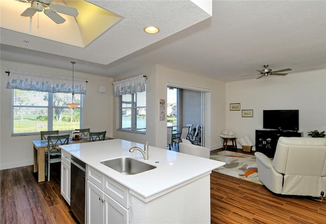 kitchen with a sink, white cabinets, open floor plan, light countertops, and an island with sink