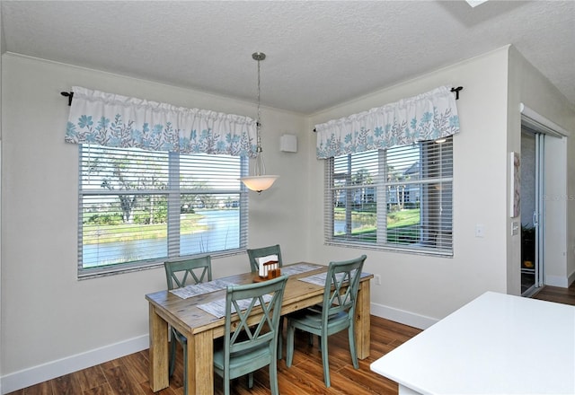 dining area with a textured ceiling, baseboards, and dark wood-type flooring