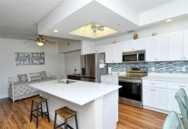 kitchen with light countertops, appliances with stainless steel finishes, a sink, and white cabinets