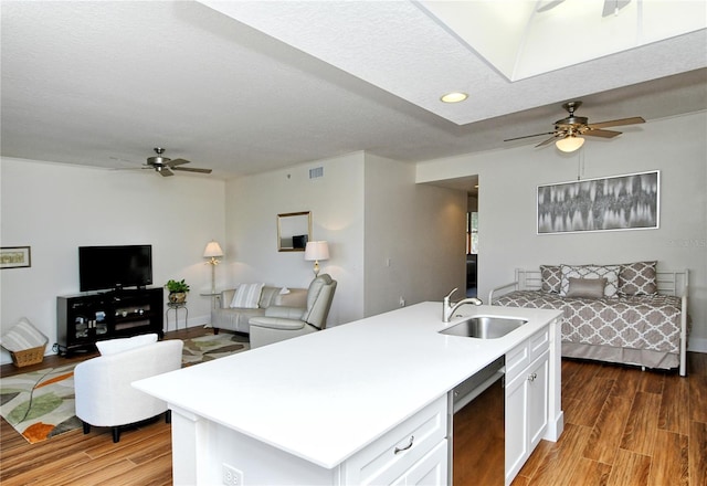 kitchen featuring black dishwasher, white cabinets, open floor plan, light countertops, and a sink