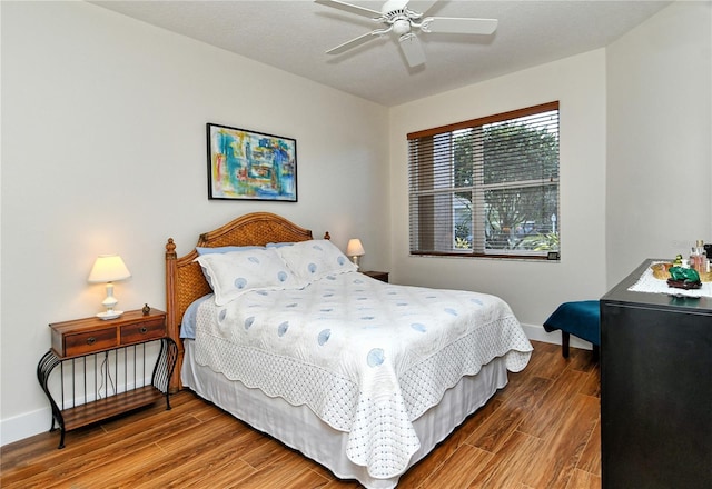 bedroom with a ceiling fan, baseboards, and wood finished floors
