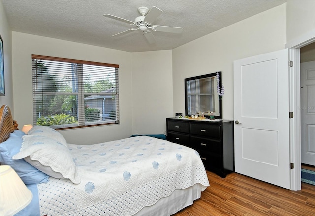 bedroom featuring a textured ceiling, a ceiling fan, and wood finished floors