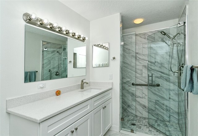 full bath featuring marble finish floor, a shower stall, a textured ceiling, and vanity