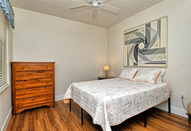 bedroom featuring a textured ceiling, baseboards, and wood finished floors