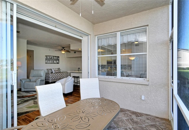 dining area with a textured wall, ceiling fan, and a textured ceiling