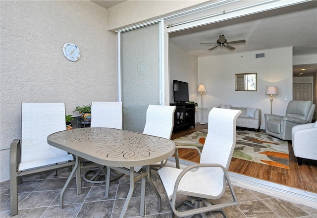 dining room featuring visible vents, a ceiling fan, and a textured wall