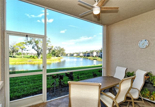 sunroom featuring a water view and a ceiling fan