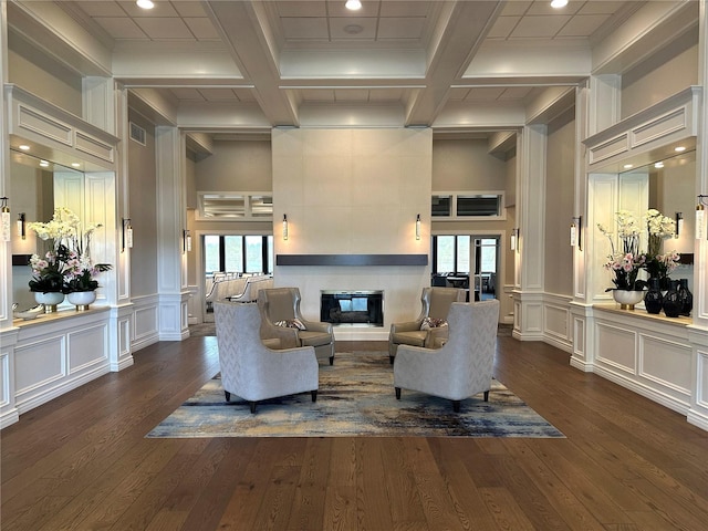 living area with dark wood finished floors, beam ceiling, a decorative wall, and a tiled fireplace