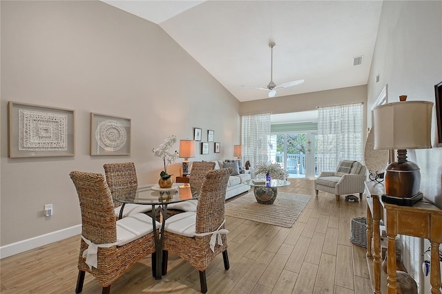 dining room with a ceiling fan, visible vents, light wood-type flooring, and high vaulted ceiling