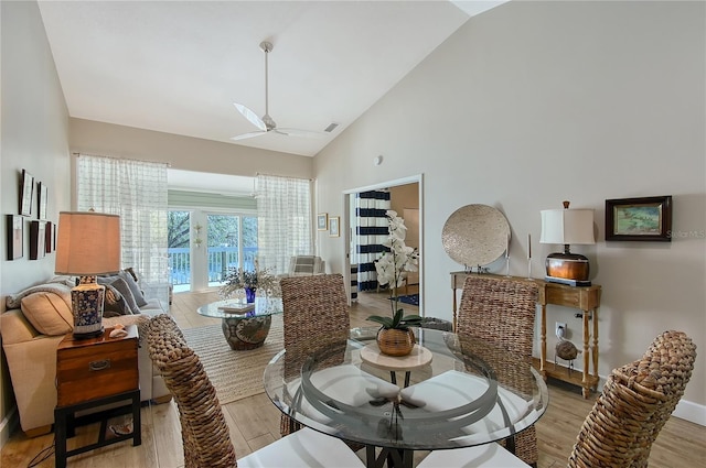 dining space featuring a ceiling fan, light wood-style floors, visible vents, and high vaulted ceiling