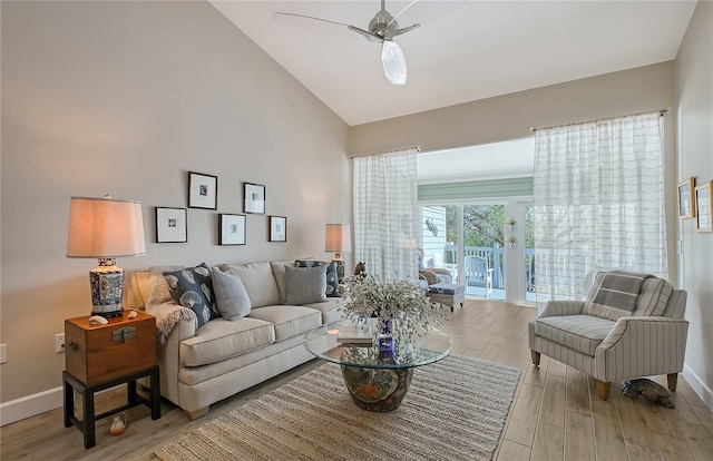 living room with baseboards, high vaulted ceiling, a ceiling fan, and light wood finished floors