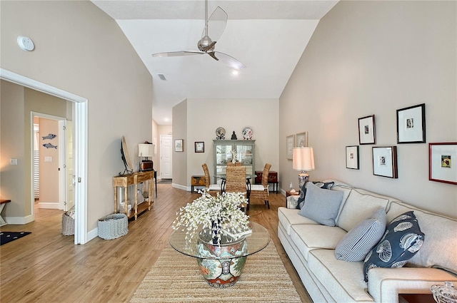 living area with light wood-style flooring, baseboards, high vaulted ceiling, and ceiling fan